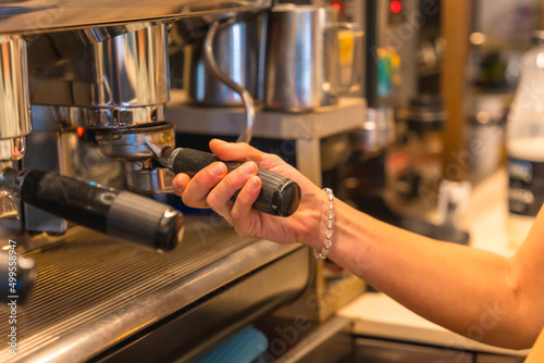 Hands of female coffee shop owner preparing coffee in a coffee machine  preparing a latte