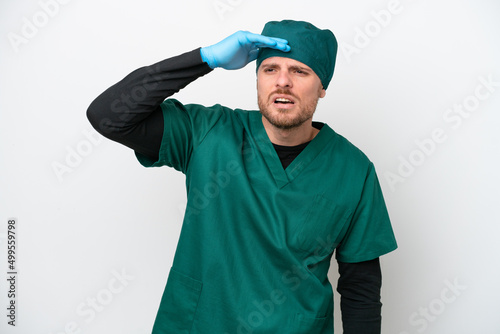 Surgeon Brazilian man in green uniform isolated on white background looking far away with hand to look something