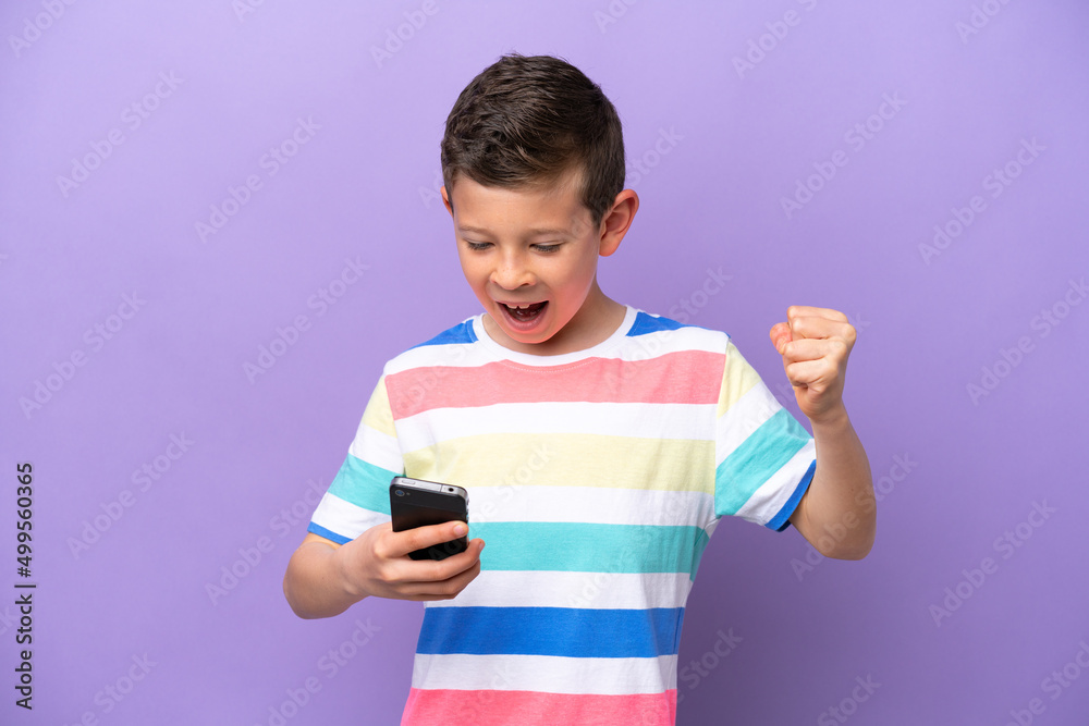 Little boy isolated on purple background with phone in victory position Little boy isolated on purple background with phone in victory position