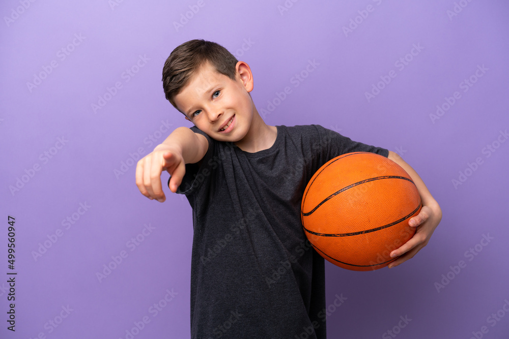 Little boy playing basketball isolated on purple background pointing front with happy expression Little boy playing basketball isolated on purple background pointing front with happy expression