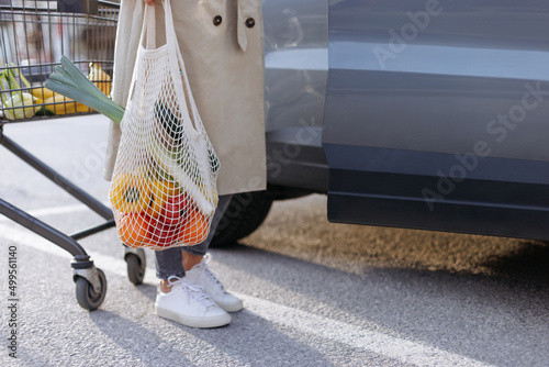 Girl holding mesh shopping bag full of organic vegetables and fruits.  Zero waste, plastic free concept. Sustainable lifestyle. Copy space.
 photo