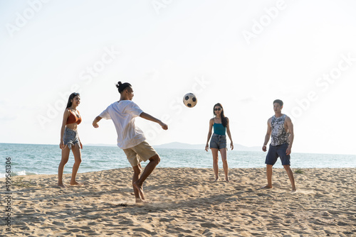 Group of Asian young man and woman play soccer on the beach together. 