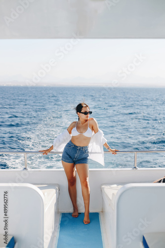 A girl with a beautiful figure in a green swimwear. She is on a white yacht in the red sea