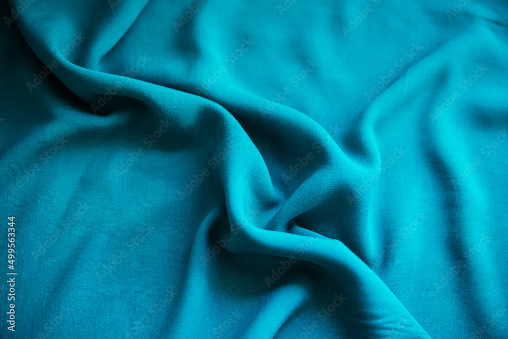 Obraz premium Blue wrinkled fabric lies in folds on the table with drapery.