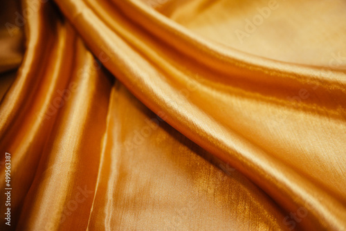 A golden wrinkled fabric lies in folds on a draped table.