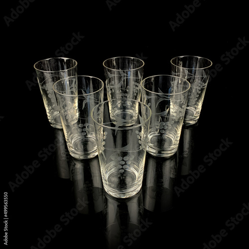 glass antique set of glasses with engraving. vintage glasses with a floral pattern on a black isolated background. table setting