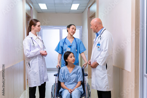 Team of doctor from different diversity is discussing with the nurse about patient in wheelchair at her appointment in hospital for physical therapy after knee surgery