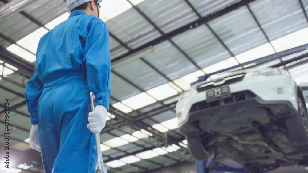 Asian automotive mechanic repairman look under car condition in garage Asian automotive mechanic repairman look under car condition in garage