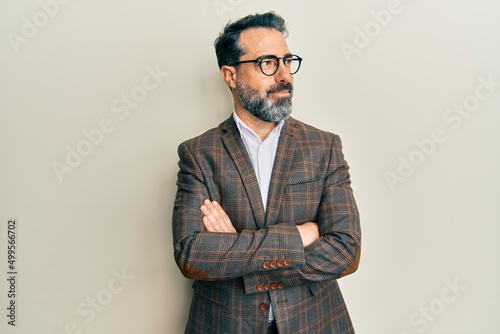 Slika na platnu Middle age man with beard and grey hair wearing business jacket and glasses smiling looking to the side and staring away thinking