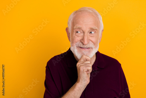 Photo of senior man curious minded plan look empty space think isolated over yellow color background