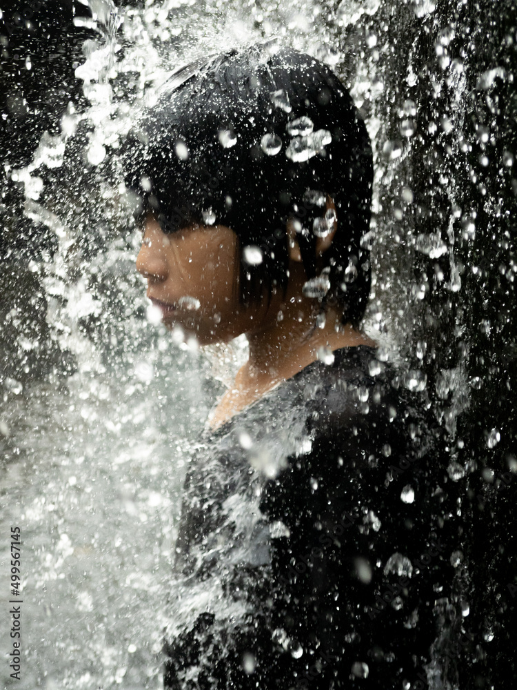 Fototapeta premium Young asian boy have fun with small waterfall