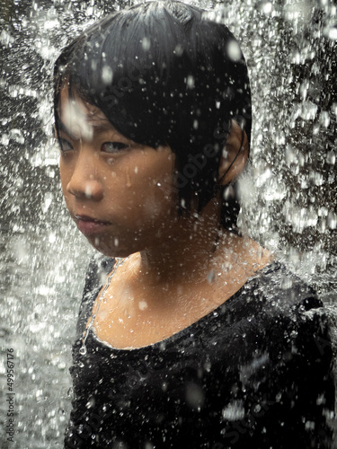 Young asian boy have fun with small waterfall