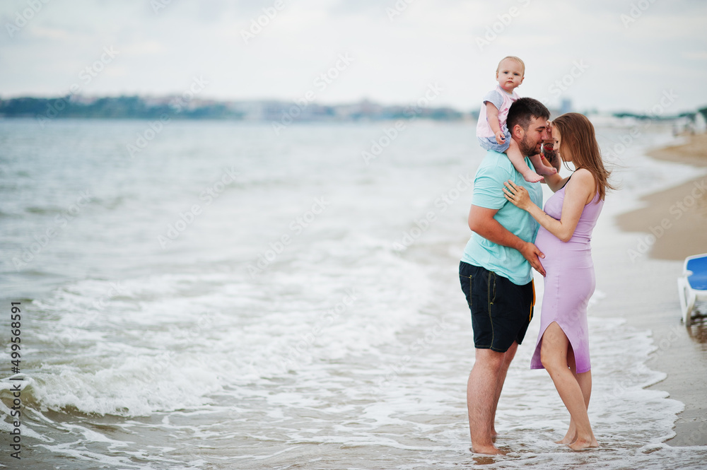 Summer vacations. Parents and people outdoor activity with children. Happy family holidays. Father, pregnant mother, baby daughter on sea sand beach. Summer vacations. Parents and people outdoor activity with children. Happy family holidays. Father, pregnant mother, baby daughter on sea sand beach.