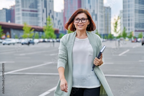 Smiling successful mature business woman walking outdoor  modern urban style background.