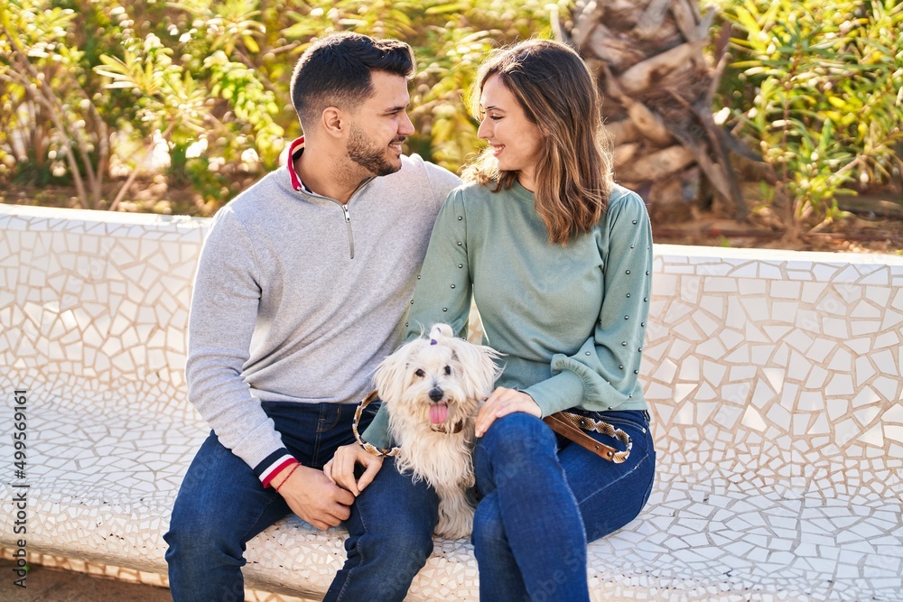 Man and woman holding dog hugging each other at park Man and woman holding dog hugging each other at park