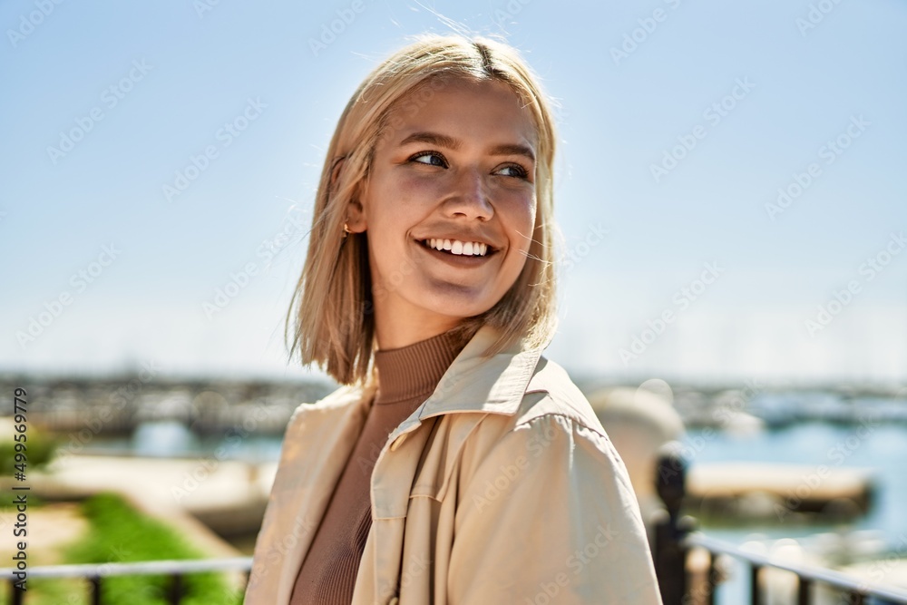 Young blonde girl smiling happy standing at the city.