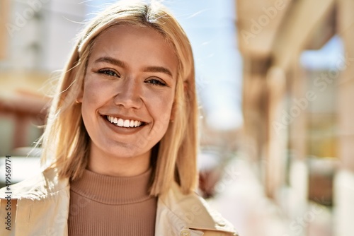 Young blonde girl smiling happy standing at the city.