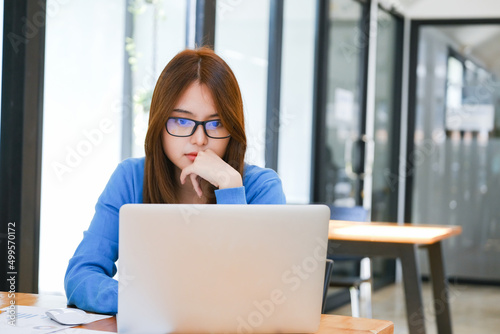 A female college student uses a computer to access the Internet for online learning.