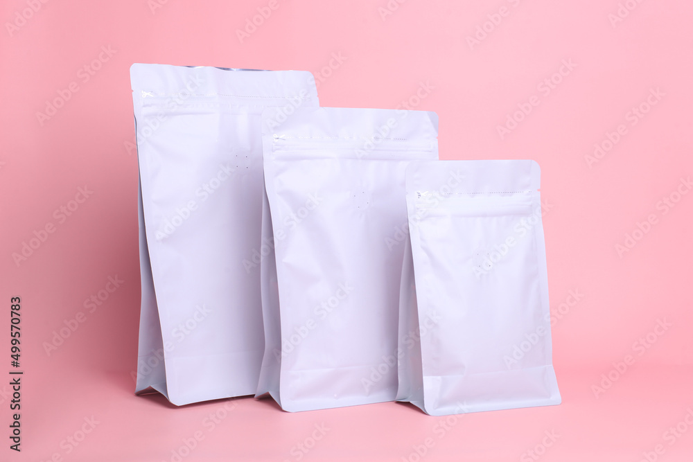 Packaging mock up for branding. White standing pouch bags with zip lock and valve on pink background, mock up for coffee packaging. 