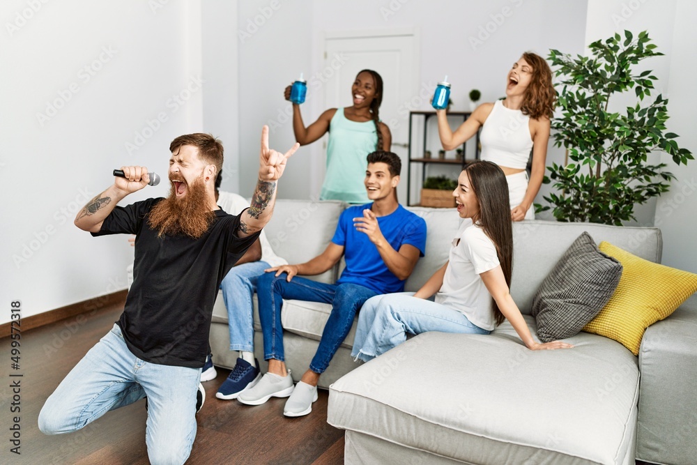 Group of young friends having party singing song using microphone at home. Group of young friends having party singing song using microphone at home.