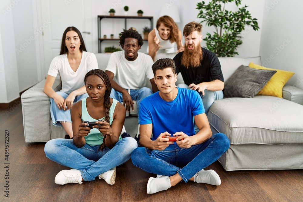 Group of young friends smiling happy playing video game at home.