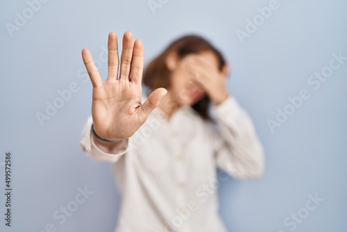 Young beautiful woman standing casual over blue background covering eyes with hands and doing stop gesture with sad and fear expression. embarrassed and negative concept.