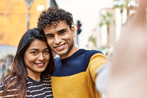 Young latin couple smiling happy and hugging make selfie by the camera at the city.