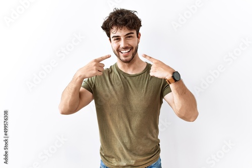 Hispanic man standing over isolated white background smiling with open mouth, fingers pointing and forcing cheerful smile © Krakenimages.com