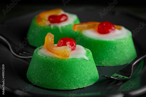 Close up of Italian dessert Cassata siciliana. Typical sicilian cheese cake made with almond, sponge cake, ricotta cheese and candied fruit, with shell of green marzipan icing. Dark background. photo