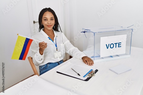 Young african american woman smiling confident holding colombia flag working at electoral college