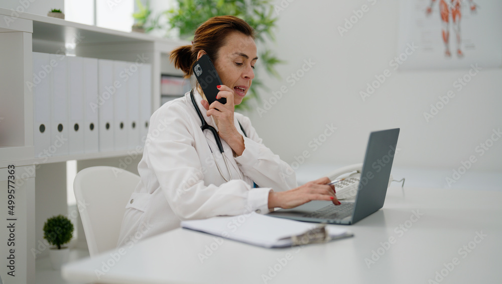 Middle age hispanic woman wearing doctor uniform talking on the smartphone at clinic Middle age hispanic woman wearing doctor uniform talking on the smartphone at clinic
