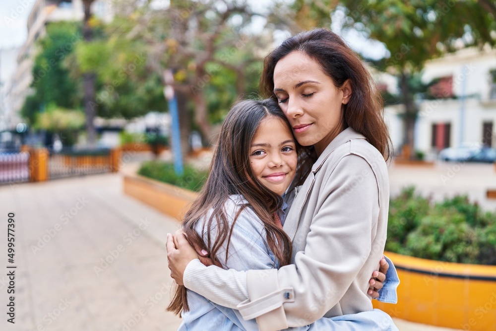Woman and girl mother and daughter hugging each other at park Woman and girl mother and daughter hugging each other at park