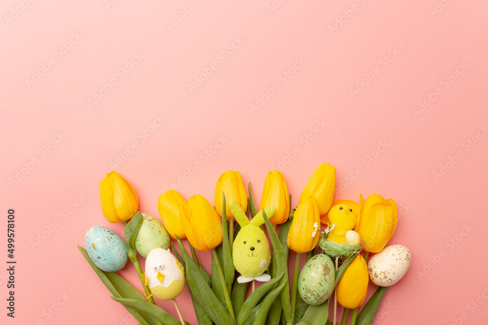 Yellow tulips and easter decor on a pink background, top view, spring bouquet. Copy space