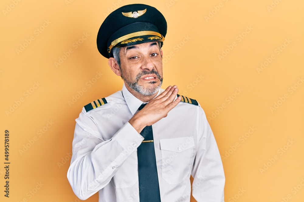 Handsome middle age man with grey hair wearing airplane pilot uniform cutting throat with hand as knife, threaten aggression with furious violence Handsome middle age man with grey hair wearing airplane pilot uniform cutting throat with hand as knife, threaten aggression with furious violence