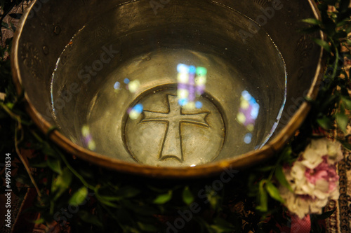 cross. detail. the cross in the baptismal font seen through the water in which the child is baptized.