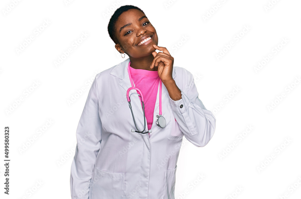 Young african american woman wearing doctor uniform and stethoscope looking confident at the camera with smile with crossed arms and hand raised on chin. thinking positive.