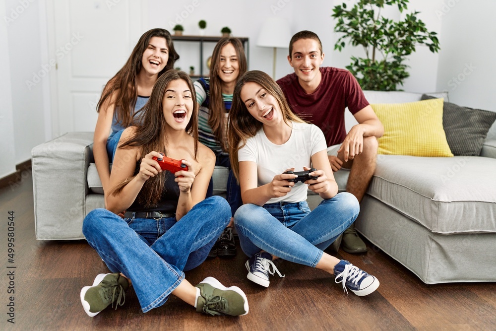 Obraz premium Group of young friends smiling happy playing video game at home.