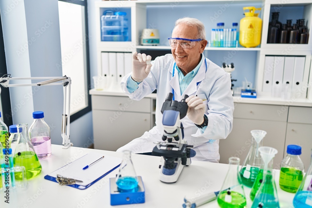 Senior man wearing scientist uniform holding sample at laboratory Senior man wearing scientist uniform holding sample at laboratory