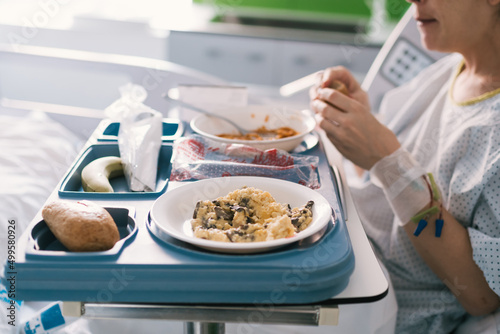 young woman who is hospitalized eating in the bed in the room the light meal that the nurses have brought her. health care and medical care in the hospital