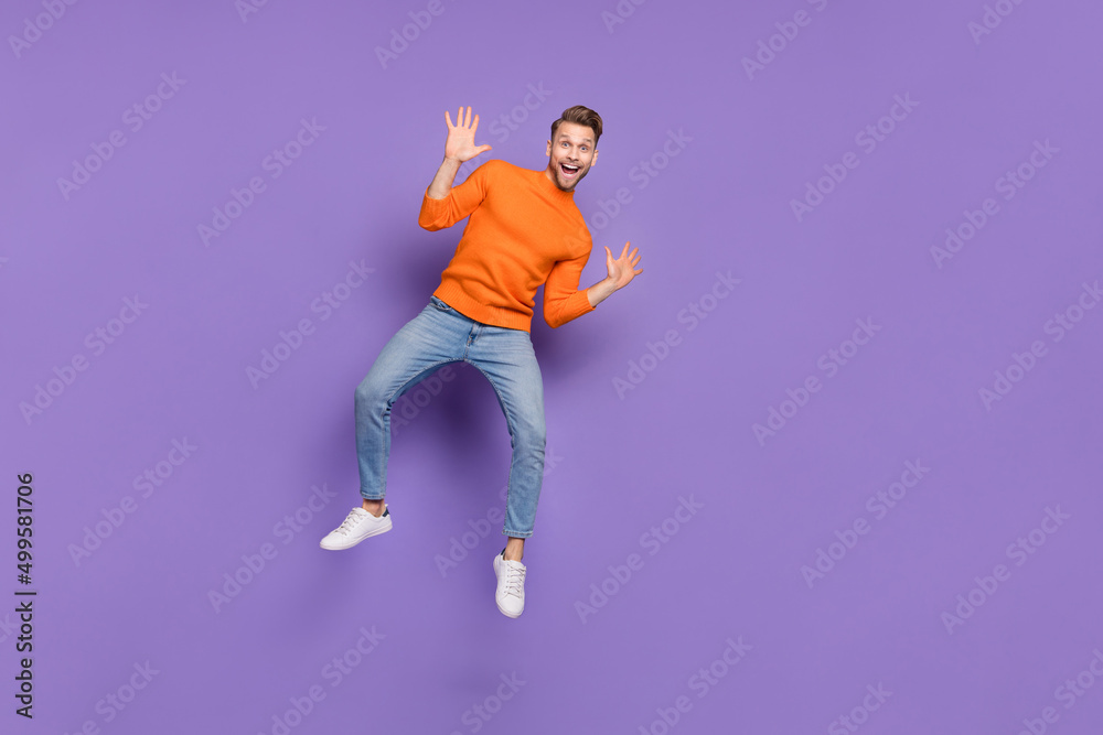 Full length photo of good mood overjoyed male jumping up wave hands say hi meet friend isolated on violet color background