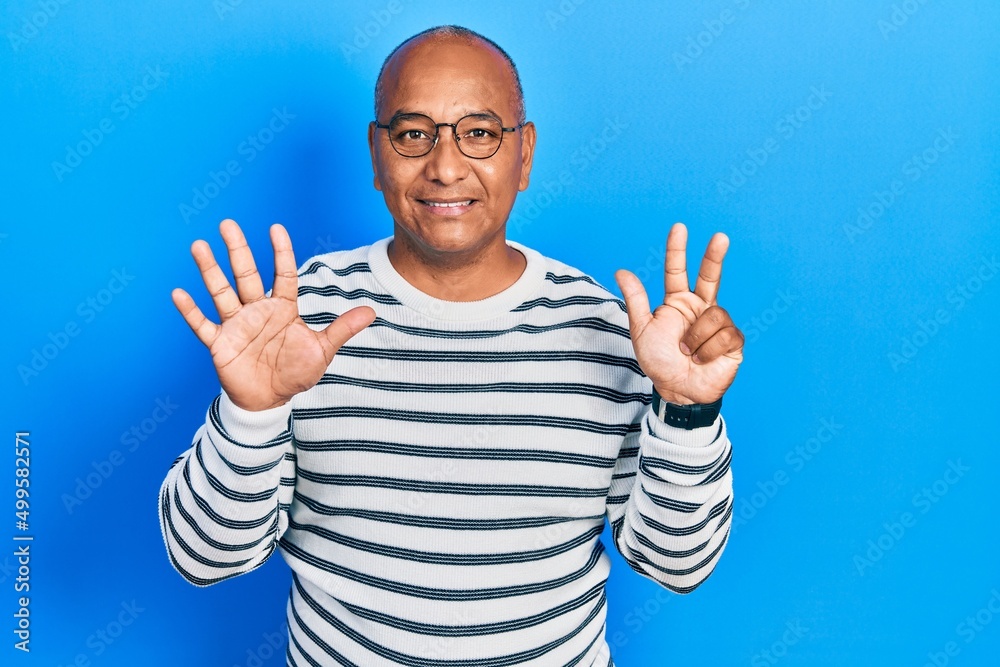Naklejka premium Middle age latin man wearing casual clothes and glasses showing and pointing up with fingers number eight while smiling confident and happy.
