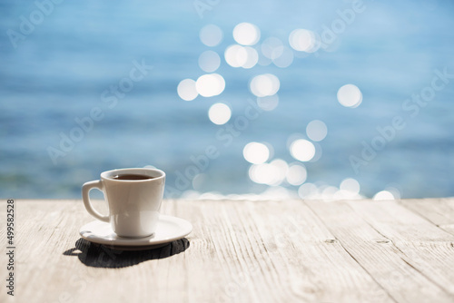 Fototapeta Naklejka Na Ścianę i Meble -  Coffee cup on wooden table over beautiful sea background. Travel background, vacations, summer fun, enjoying life, relaxation, happiness, lifestyle concept.