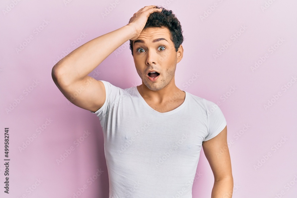 Young handsome man wearing casual white t shirt surprised with hand on head for mistake, remember error. forgot, bad memory concept. Young handsome man wearing casual white t shirt surprised with hand on head for mistake, remember error. forgot, bad memory concept.