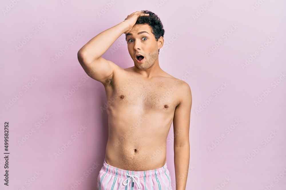 Fototapeta premium Young handsome man wearing swimwear shirtless surprised with hand on head for mistake, remember error. forgot, bad memory concept.