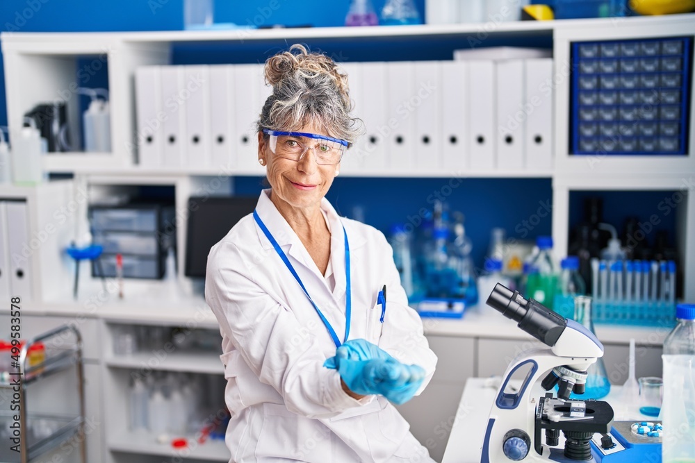 Middle age woman scientist wearing gloves at laboratory