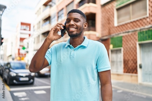Young african american man smiling confident talking on the smartphone at street