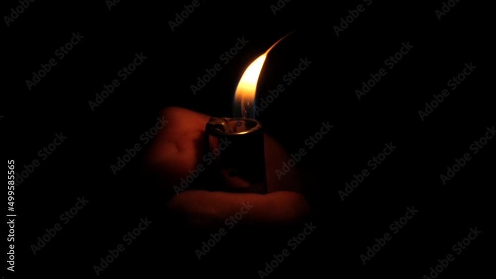 Close up hand igniting lighter on black background, slow motion Close up hand igniting lighter on black background, slow motion