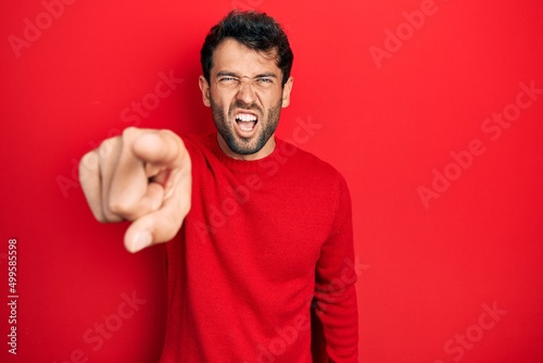 Handsome man with beard wearing casual red sweater pointing displeased and frustrated to the camera, angry and furious with you © Krakenimages.com