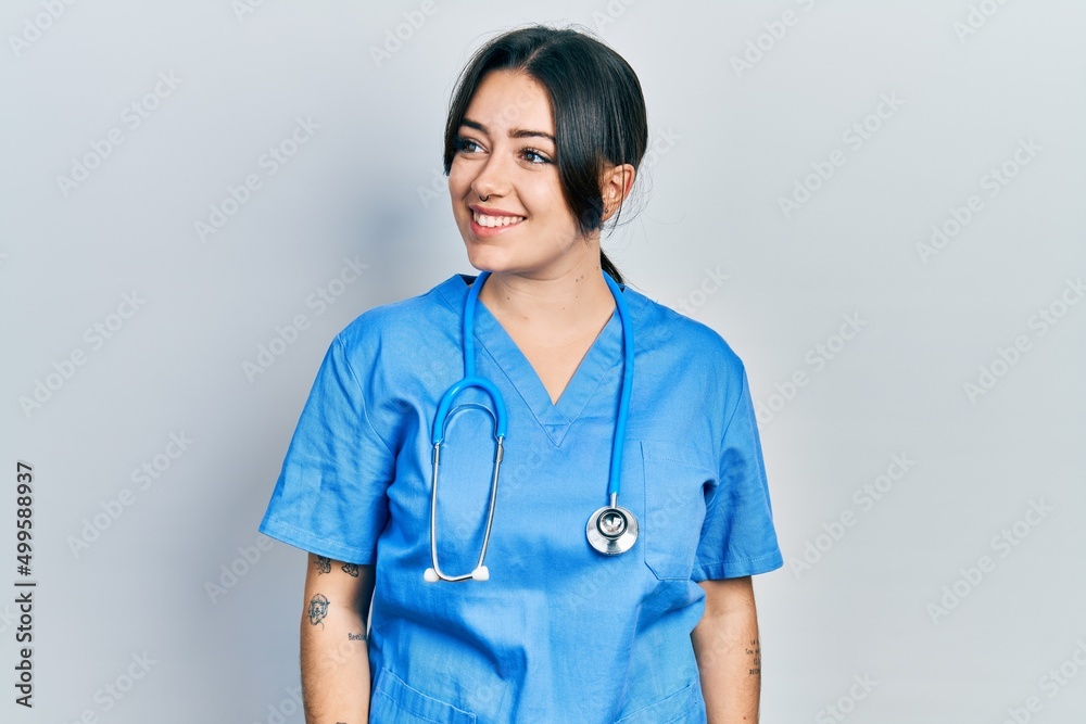 Beautiful hispanic woman wearing doctor uniform and stethoscope looking to side, relax profile pose with natural face and confident smile. Beautiful hispanic woman wearing doctor uniform and stethoscope looking to side, relax profile pose with natural face and confident smile.