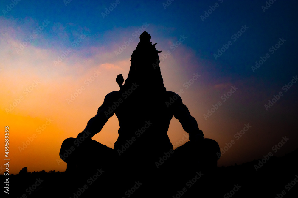back lit statue of hindu god lord shiva in meditation posture with dramatic sky from unique angle - obrazy, fototapety, plakaty 